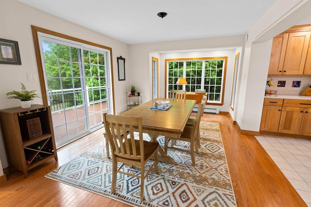 dining space with light wood-style floors, a baseboard radiator, and plenty of natural light