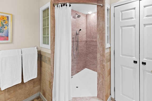 full bathroom with a tile shower and tile walls