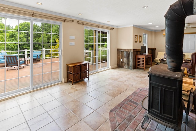 living room with a wainscoted wall, recessed lighting, a wood stove, and crown molding