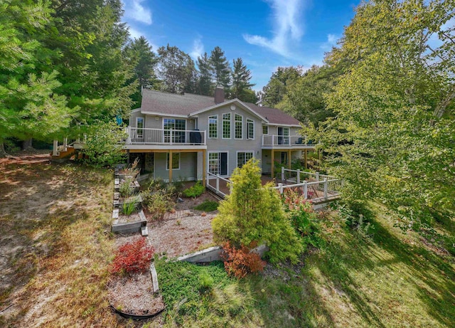 view of front facade featuring a chimney, a vegetable garden, and a wooden deck