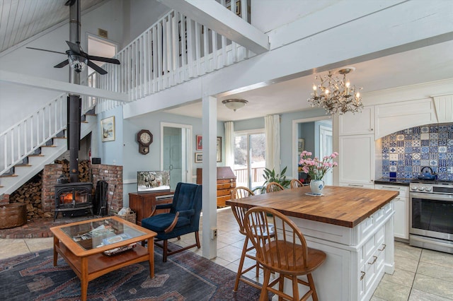 kitchen with a breakfast bar area, white cabinets, open floor plan, wooden counters, and stainless steel electric range oven