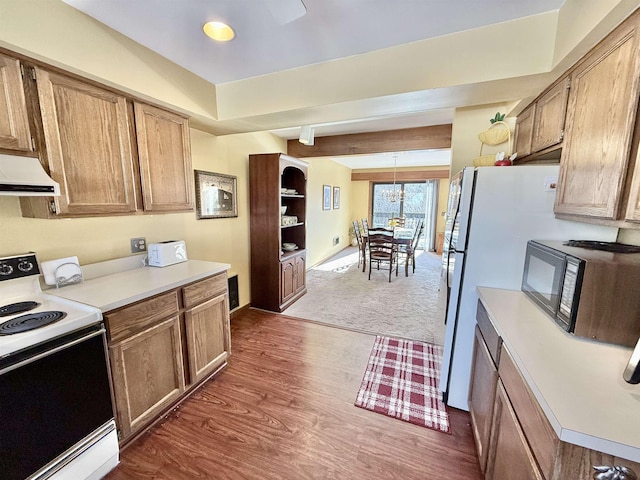 kitchen featuring range hood, electric stove, light countertops, black microwave, and beamed ceiling