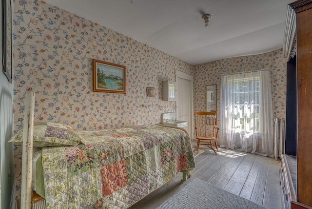 bedroom with wallpapered walls and hardwood / wood-style flooring