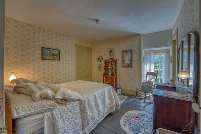 bedroom featuring baseboards, hardwood / wood-style floors, and wallpapered walls