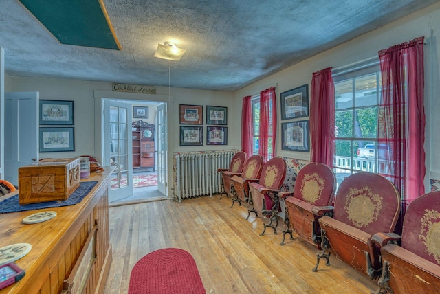 sitting room featuring a textured ceiling, light wood-type flooring, and radiator