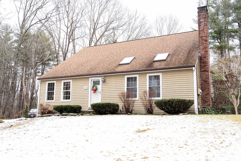 view of front of house with roof with shingles and a chimney