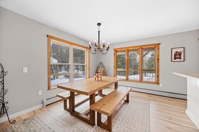 dining area featuring light wood finished floors, baseboards, baseboard heating, and a notable chandelier