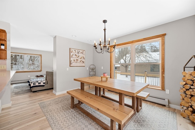 dining room with a baseboard radiator, a notable chandelier, light wood-style flooring, and baseboards