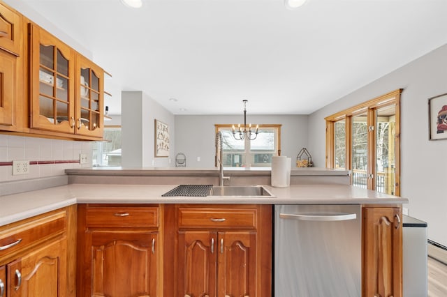 kitchen with light countertops, stainless steel dishwasher, a sink, and glass insert cabinets