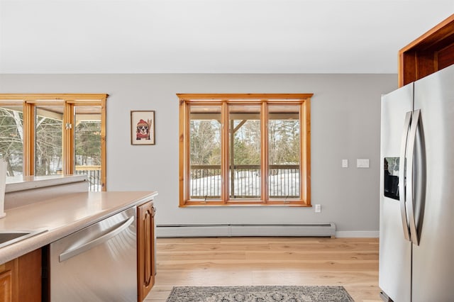 kitchen featuring a baseboard heating unit, stainless steel appliances, light wood-style floors, and a healthy amount of sunlight