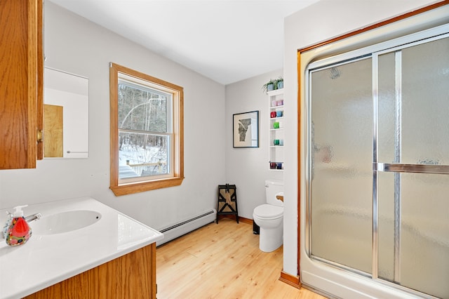 full bath with a baseboard radiator, toilet, wood finished floors, vanity, and a shower with door