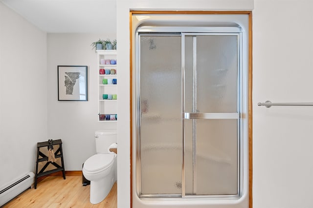 bathroom with a baseboard heating unit, a stall shower, wood finished floors, and toilet