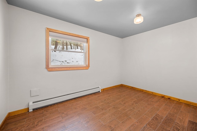 empty room featuring baseboards, a baseboard heating unit, and wood finished floors