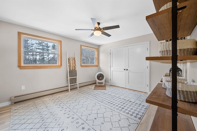 interior space featuring ceiling fan, baseboard heating, light wood-style flooring, and baseboards