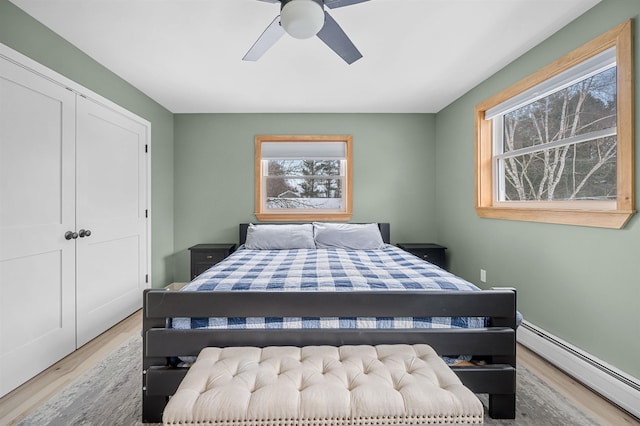 bedroom featuring ceiling fan, a baseboard heating unit, and wood finished floors