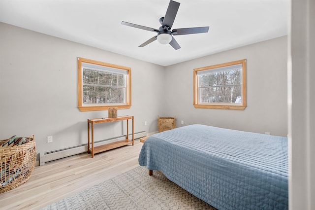 bedroom with a ceiling fan, a baseboard heating unit, and wood finished floors