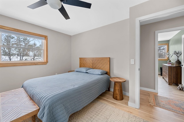 bedroom with light wood finished floors, multiple windows, and baseboards