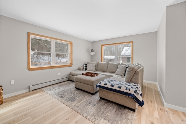 living room with a baseboard heating unit, wood finished floors, and baseboards