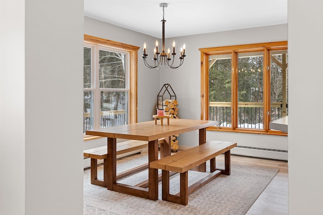 dining room with a baseboard radiator, wood finished floors, and an inviting chandelier