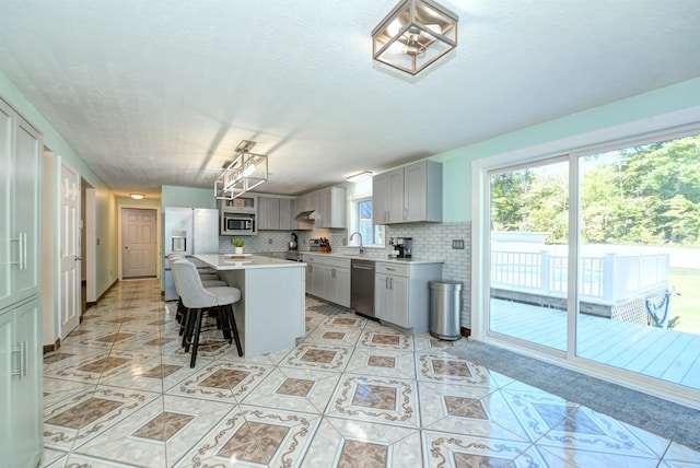 kitchen featuring a breakfast bar, light tile patterned floors, stainless steel appliances, gray cabinets, and light countertops