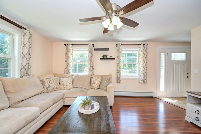 living room featuring a healthy amount of sunlight, a baseboard radiator, a ceiling fan, and dark wood-type flooring