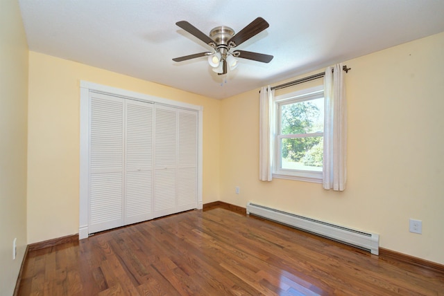 unfurnished bedroom with a closet, a baseboard heating unit, a ceiling fan, wood finished floors, and baseboards