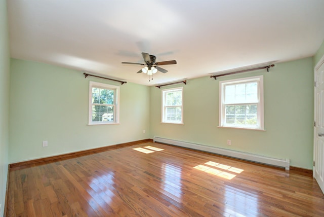 unfurnished room featuring baseboard heating, wood-type flooring, and baseboards