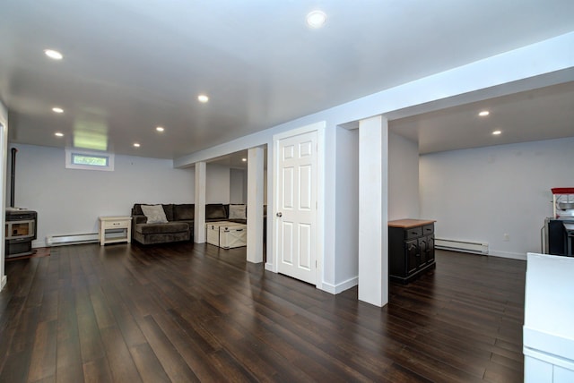 interior space featuring dark wood-style floors, a baseboard radiator, a wood stove, and recessed lighting