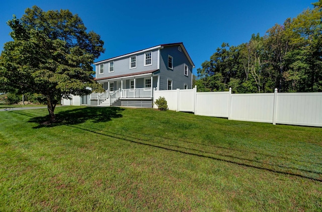 rear view of property featuring a garage, covered porch, fence, and a lawn