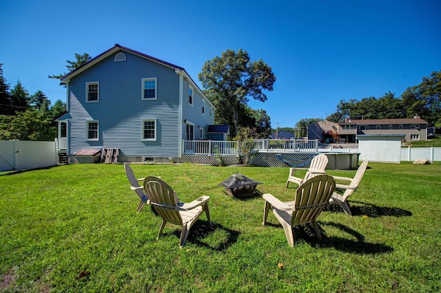 view of yard with a fenced in pool, a fenced backyard, a fire pit, and a storage unit