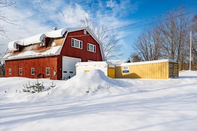 exterior space with a garage, a gambrel roof, an outbuilding, and a barn