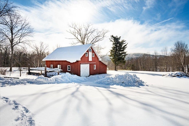 snow covered structure featuring an outbuilding and a barn