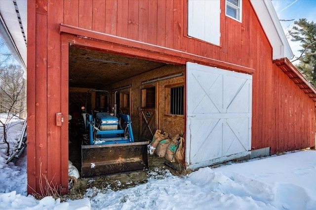 snow covered structure featuring a garage and an outdoor structure