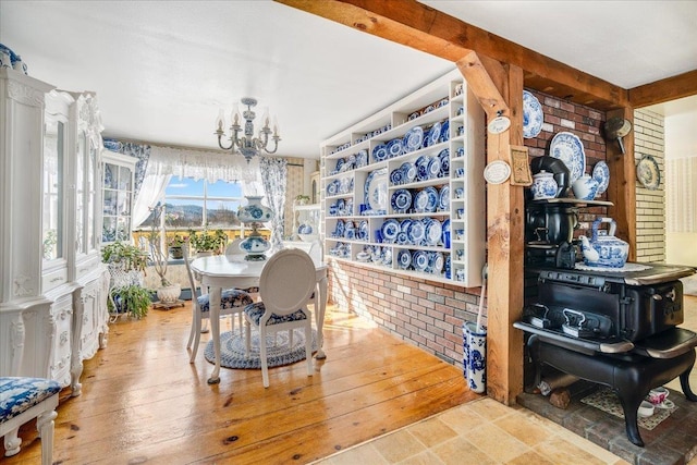 dining area featuring hardwood / wood-style flooring, brick wall, and an inviting chandelier