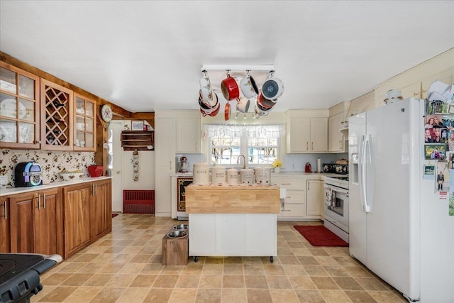 kitchen with white appliances, beverage cooler, brown cabinetry, glass insert cabinets, and a center island