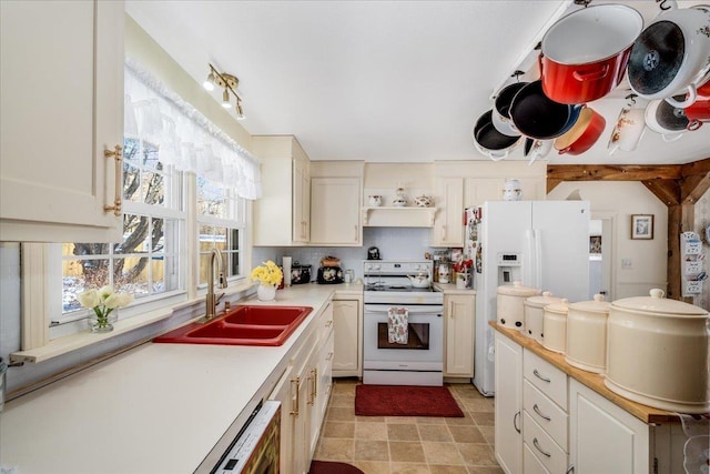 kitchen featuring light countertops, decorative backsplash, white cabinets, a sink, and white appliances