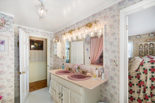 bathroom featuring double vanity, wallpapered walls, a sink, and wainscoting