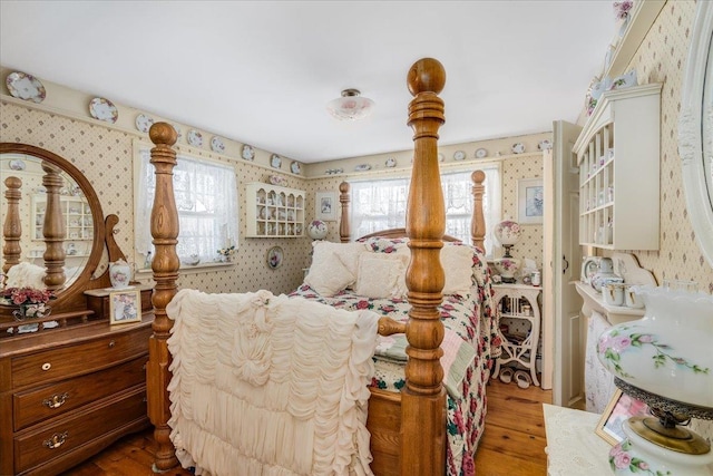 bedroom with wood finished floors and wallpapered walls