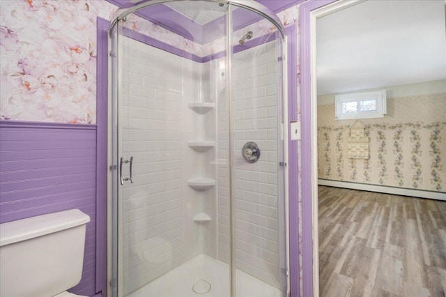 bathroom with a wainscoted wall, a shower stall, toilet, and wallpapered walls