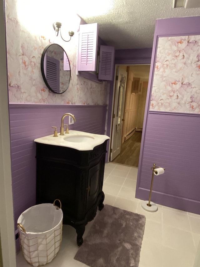 bathroom with a wainscoted wall, a textured ceiling, a wood stove, and wallpapered walls