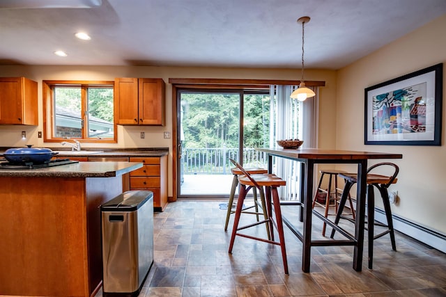 kitchen featuring recessed lighting, a sink, brown cabinetry, dark countertops, and pendant lighting