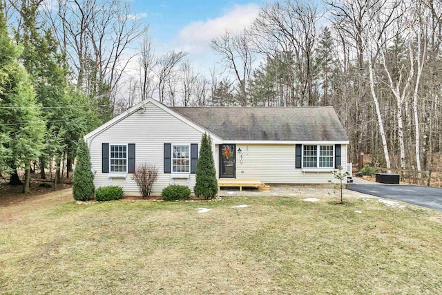 single story home featuring a shingled roof, aphalt driveway, and a front yard