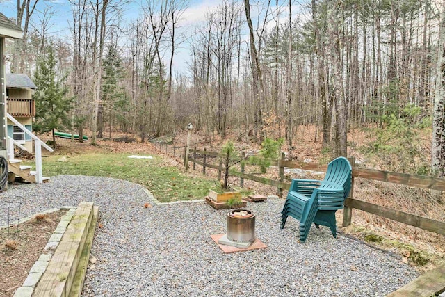 view of yard with stairs, a wooded view, and fence