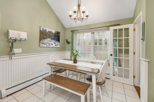 dining room with light tile patterned floors, lofted ceiling, a wainscoted wall, baseboard heating, and an inviting chandelier