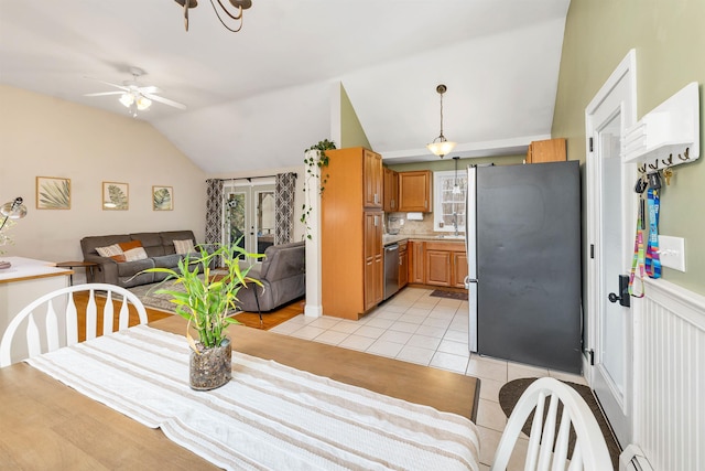 dining room with light tile patterned floors, a baseboard radiator, a wainscoted wall, a ceiling fan, and vaulted ceiling