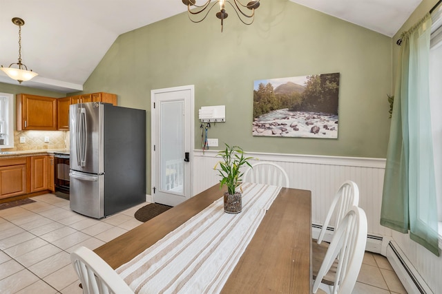 dining room with a wainscoted wall, vaulted ceiling, baseboard heating, and light tile patterned floors