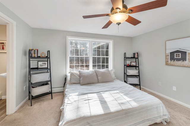 bedroom with a baseboard heating unit, light colored carpet, ceiling fan, and baseboards