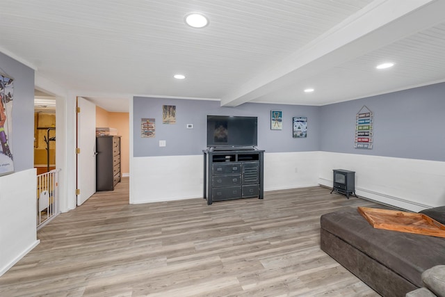 living area with a baseboard heating unit, recessed lighting, a wood stove, and wood finished floors