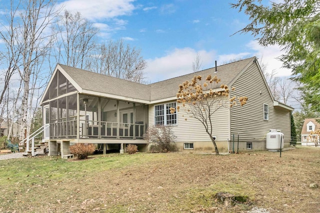 back of house featuring roof with shingles, a lawn, and a sunroom