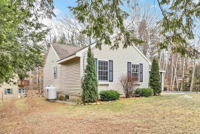 view of side of property with roof with shingles and a yard